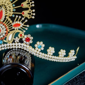 Close-up of golden bridal crown with red and blue gemstones and elegant white pearls