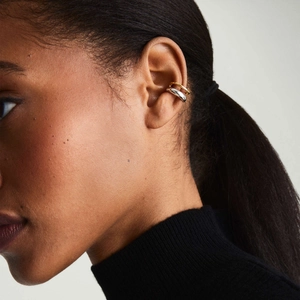 Close-up of minimalist gold and silver ear cuff set on a model with a dark skin tone