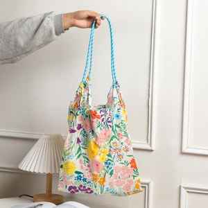 Detail of floral cotton tote bag with woven blue and white checkered handles
