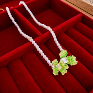 Macro shot of butterfly pendant necklace with green crystals on red velvet lining