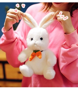 Close-up of white plush bunny with cute orange carrot accessories and soft long fur