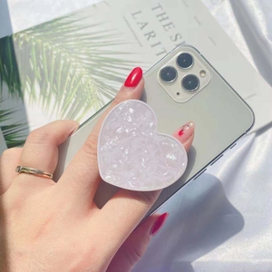 Pale pink heart-shaped phone grip with crushed ice texture on a green smartphone