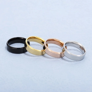 Polished stainless steel rings in black, gold, rose gold and silver on blue surface
