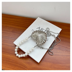 Detail of silver heart shaped mini evening bag with pleated metal texture and pearl handle