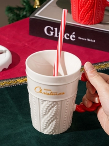 Detail of white ceramic Christmas mug with red knit-textured handle and gold lettering