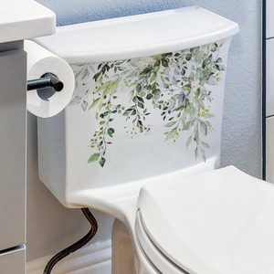 Detailed view of green leaf and flower decals on a white ceramic toilet tank surface