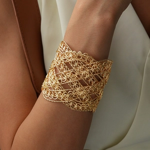 Detailed macro view of a gold-plated woven mesh cuff bracelet with intricate layered design