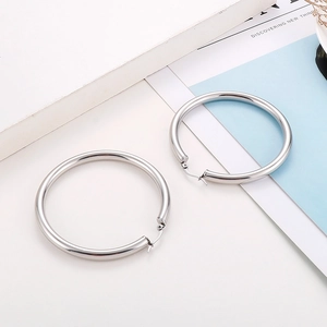 Macro detail of thick silver stainless steel hoop earrings with latch back closure