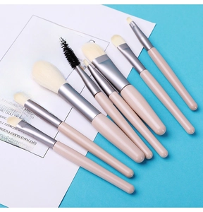 Detail view of 8-piece makeup brush set with matte pink handles on light blue background