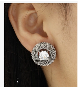 Close-up of vintage oval silver mesh earring with transparent crystal on female ear