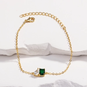 Détail du bracelet doré avec zircon vert émeraude et pierre en forme de goutte d'eau