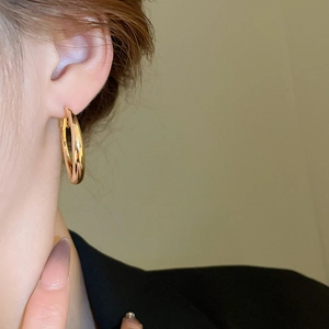 Close-up of polished golden hoop earrings worn by a model for a modern minimalist style
