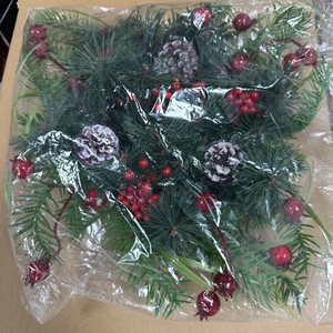 Detailed view of Christmas wreath accessories with pine cones, needles, and red berries
