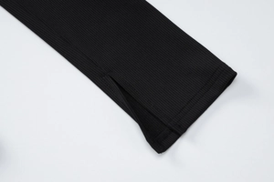 Nahaufnahme der gerippten Strickstruktur und Schlitz-Manschette eines schwarzen Kleides