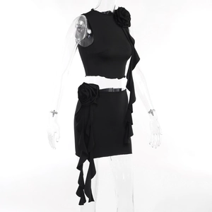 Detail of black two-piece skirt set featuring a 3D rose accent and ruffled hemline