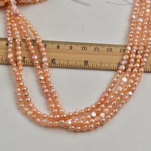Macro shot of 4-5mm pink freshwater baroque pearls with a wooden ruler for size scaling