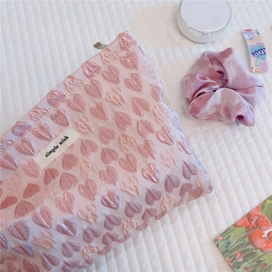 Close-up of pink heart jacquard fabric cosmetic bag with a simple wish woven label