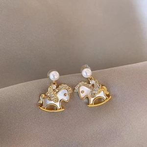 Gold plated rocking horse earrings with shell inlay and pearls on silk fabric
