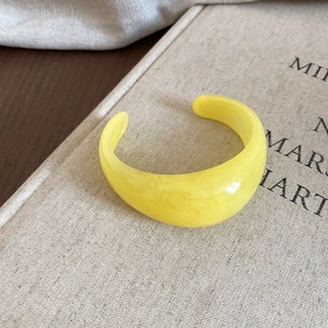 Detailed view of wide yellow resin cuff bracelet with marble texture on linen cover