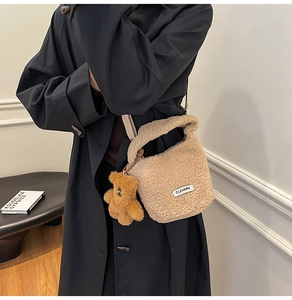 Detail of soft lamb wool bucket bag with cute bear charm and woven canvas shoulder strap