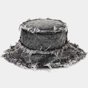 Macro shot of frayed edges and worn denim texture on a dark grey vintage bucket hat