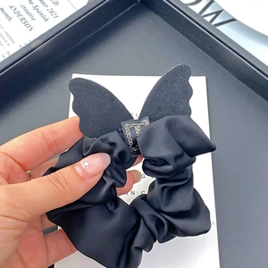 Detail of elegant black silk scrunchie featuring a delicate butterfly wing ornament