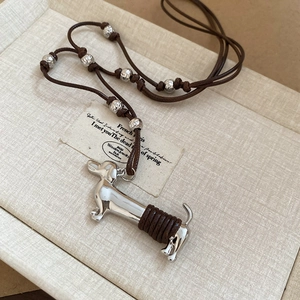 Silver dachshund pendant necklace with dark brown adjustable cord on beige gift box