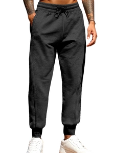 Detail of men's black joggers showing elastic waistband with drawstring and knit fabric