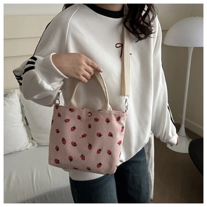 Pink corduroy tote bag featuring red strawberry patterns and adjustable straps