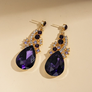 Macro view of teardrop purple crystals on gold drop earrings with vintage court style detail