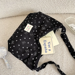 Macro shot of black corduroy shoulder bag with white bow prints on soft textured rug