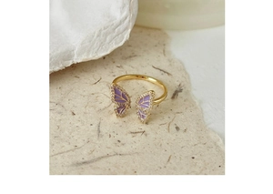 Detail of a vintage golden butterfly ring with purple enamel wings and zircon stones