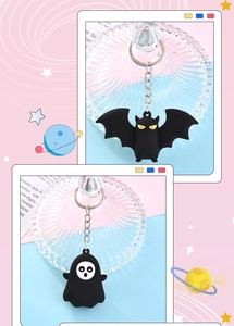 Close-up of black cartoon bat and ghost keychain pendants with silver metal rings