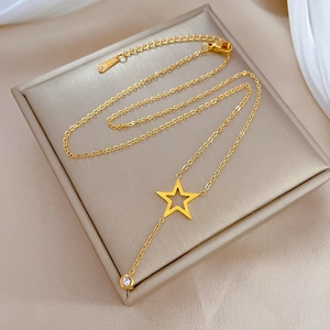 Detailed macro view of gold star pendant necklace with zircon and S.STEEL hallmark