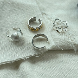 Close-up of assorted 925 silver and gold rings with vintage textures on linen fabric