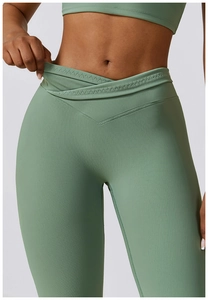Détail du pantalon de yoga évasé montrant la taille croisée en V et le tissu côtelé vert