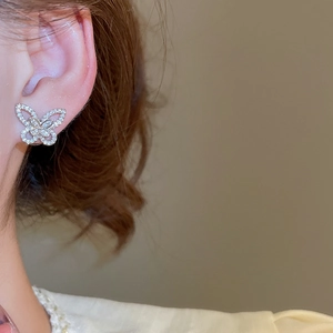 Close-up of elegant butterfly ear stud with pavé cubic zirconia on model's ear