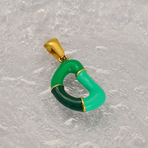 Macro shot of abstract green enamel geometric charm with gold-plated titanium steel edge