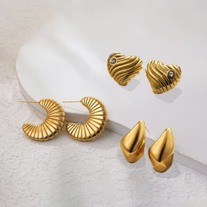 Detailed macro view of three 18K gold-plated stainless steel earrings with heart and ripple designs
