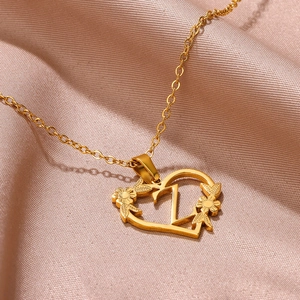 Dettaglio del ciondolo a cuore dorato con lettera Z e fiori su sfondo di seta