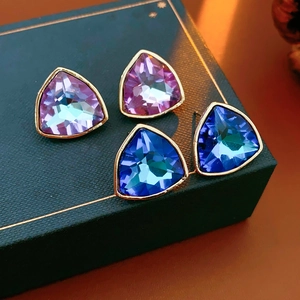 Détail de boucles d'oreilles triangles avec strass dégradés violets et bleus sur boîte