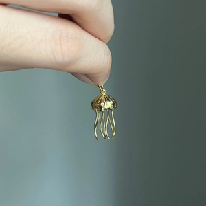 Detailed view of a golden jellyfish pendant with diamond accents and baroque pearls