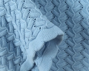 Vue macro détaillée du tricot au crochet bleu clair avec motifs ajourés ondulés