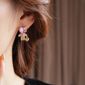 Detail of bear stud earring with pink zircon stone and heart pendant on ear