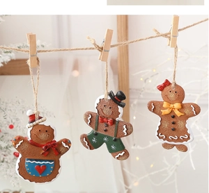 Three gingerbread man resin pendants with festive aprons hanging on a rustic hemp rope