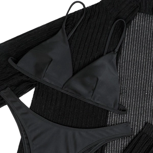 Detail of black bikini set layered on a mesh crochet cover-up with high-cut design
