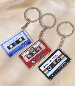 Close-up of vintage cassette tape keychains in blue, red, and black on silk fabric
