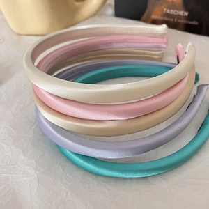Detailed overhead view of multiple glossy satin padded headbands in assorted pastel colors