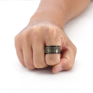 Detail of golden honeycomb pattern on black titanium steel spinning ring for men