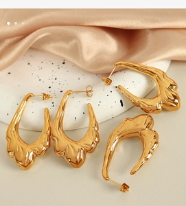 Macro detail of molten texture gold earrings on elegant silk and ceramic plate background